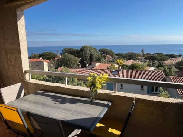 Vue mer panoramique Terrasse Piscine Clim Parking Vue sur la mer depuis un balcon avec une table, des chaises et des fleurs.