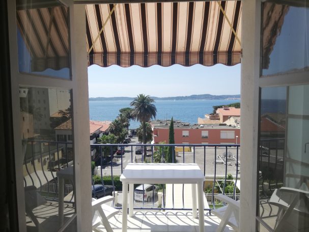 Sainte Maxime: studio vue mer Vue d'une terrasse avec des chaises, surplombant la mer et des bâtiments.