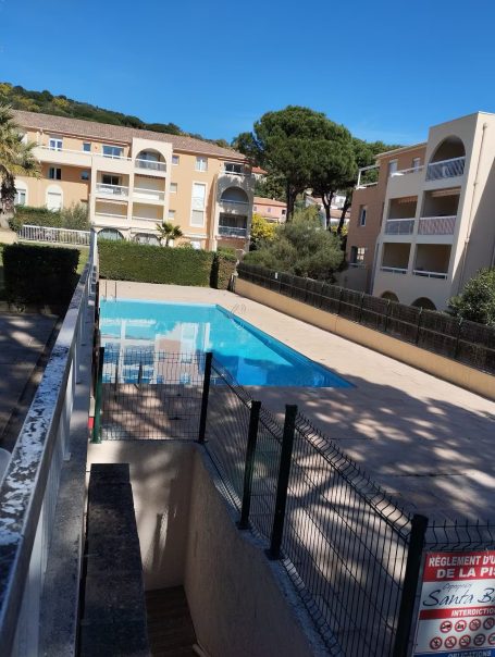 Santa Barbara T3 : clim, piscine, terrasse, wifi Piscine entourée d'appartements, ciel bleu et verdure en arrière-plan.