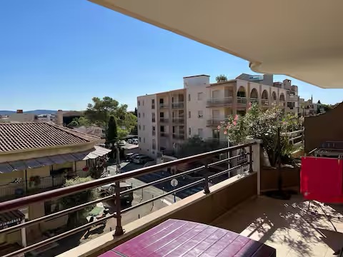 Evasion à Cavalaire : T2, garage, 600m de la plage Vue ensoleillée d'une rue avec des bâtiments et un balcon.