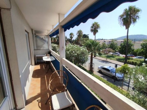 Hyères: T2 terrasse, proche piscine et jardin Olbus Riquier Balcon avec chaises, palmier, vue sur rue et montagnes en arrière-plan.