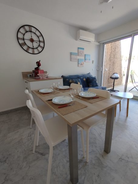 Cavalaire : T2, terrasse, face au port Salle à manger moderne avec table en bois, chaises blanches et décor minimaliste.