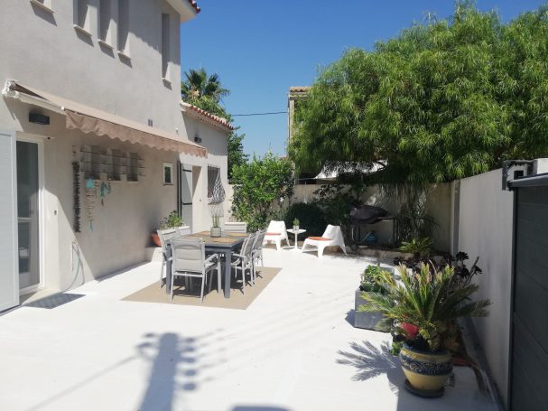 Hyères : T2 dans villa, bord de mer Terrasse ensoleillée avec mobilier de jardin et plantes en pot.