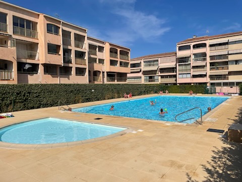 Sainte Maxime: T2 véranda, piscine Deux piscines entourées d'immeubles avec des personnes profitant du soleil.
