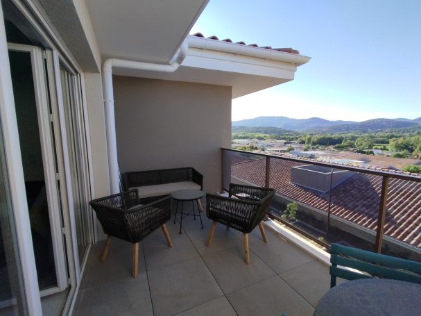 Cogolin: spacieux T2 neuf, terrasse, mer à 10' Balcon avec vue sur les montagnes, équipé de chaises et d'une table.