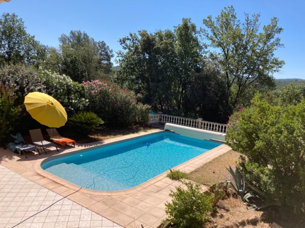 Provence Verte: villa T4, jardin, piscine. Piscine entourée de verdure et parasol, ciel bleu clair.